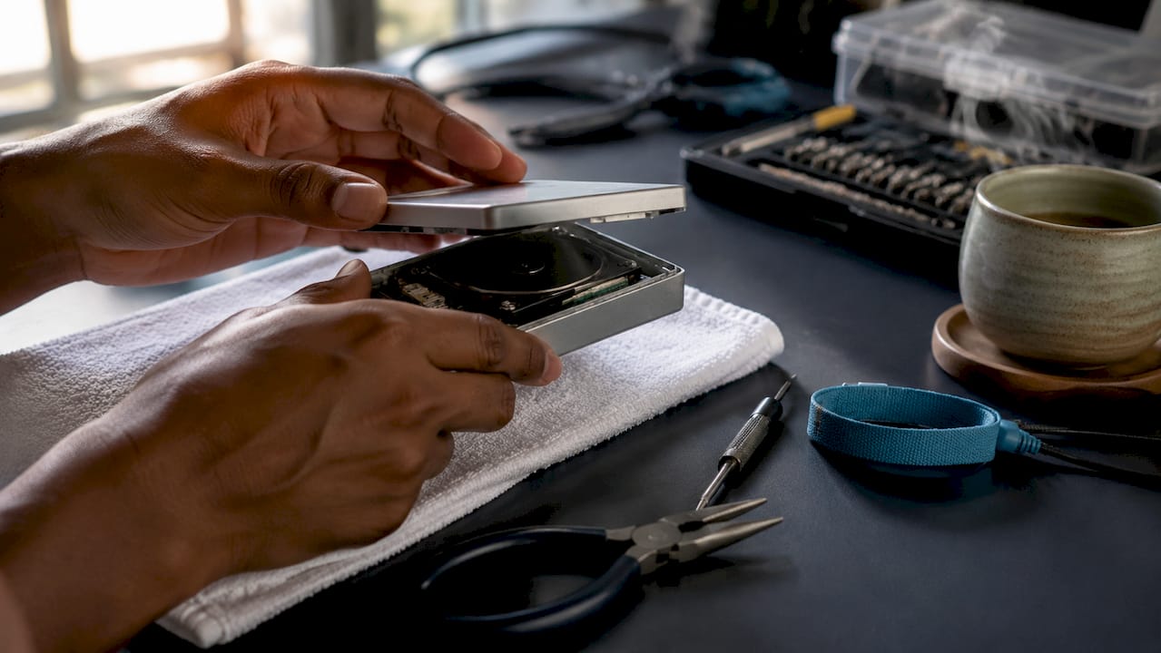 Hands repairing LaCie external hard drive with tools