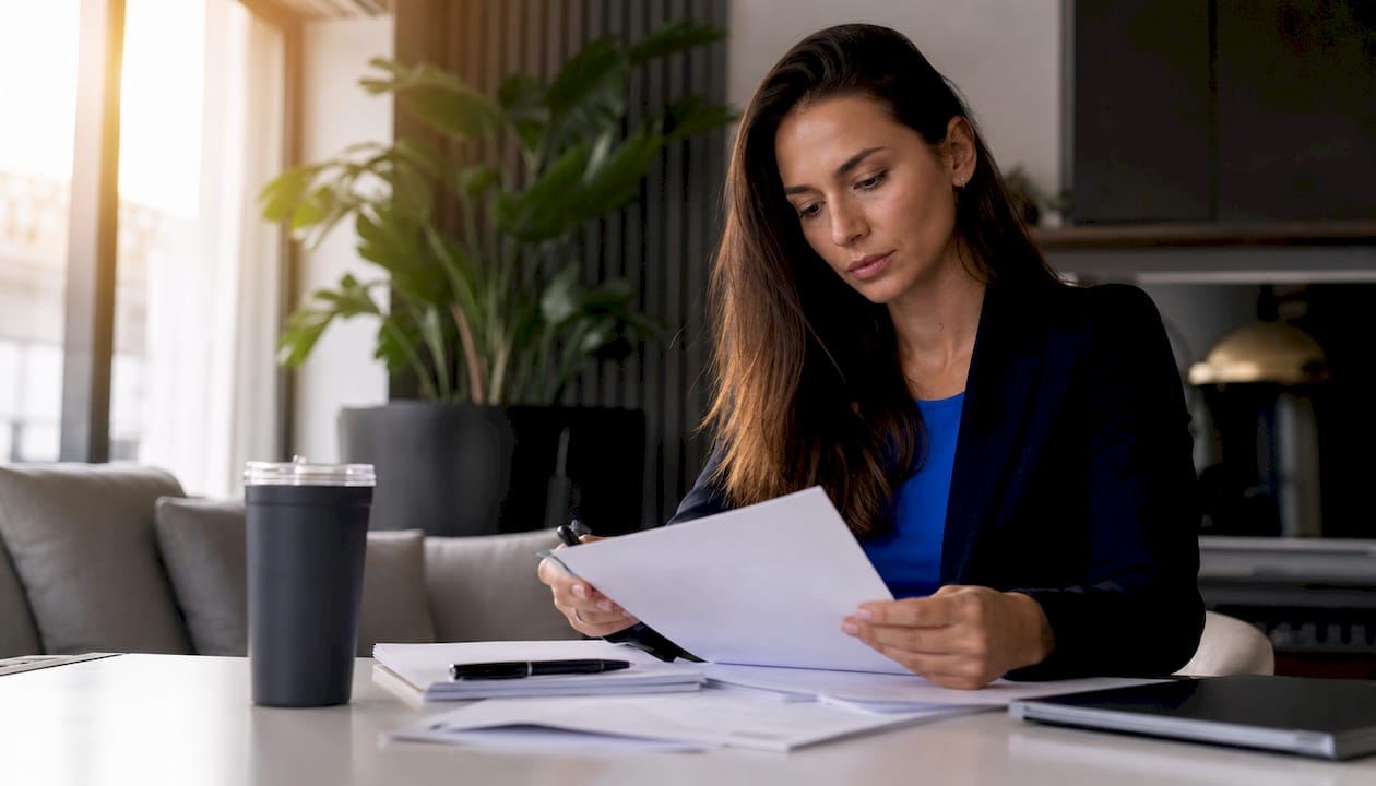 Een ondernemer bladert thuis aan de keukentafel door de VOF-contracten.