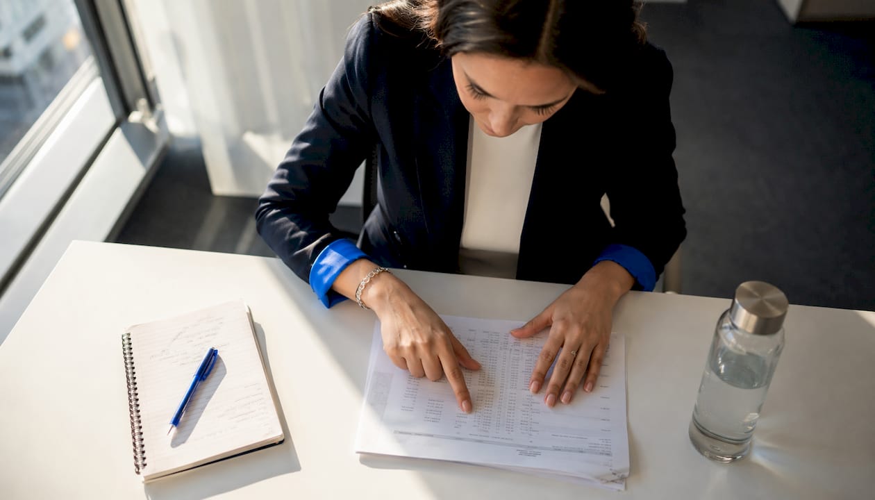 Een paar handen over een belastingformulier, liggend op een bureaublad.