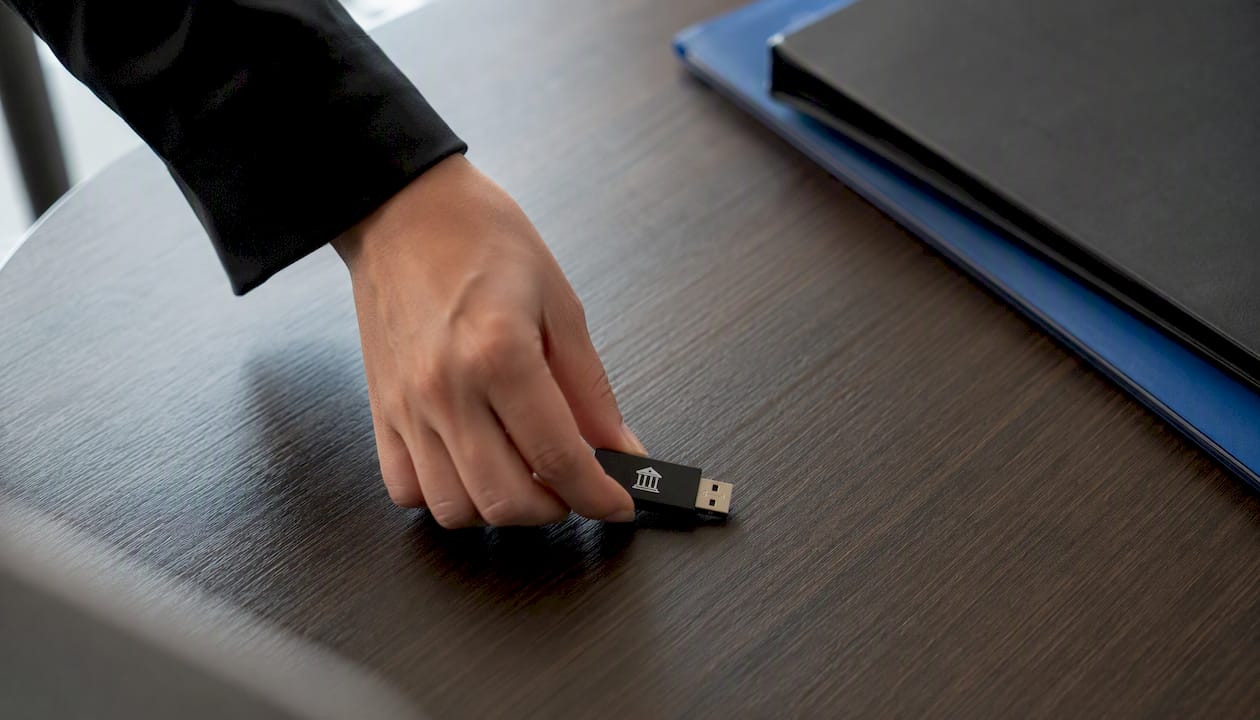 Iemand steekt een USB-stick in een computer tijdens een vergadering op kantoor.
