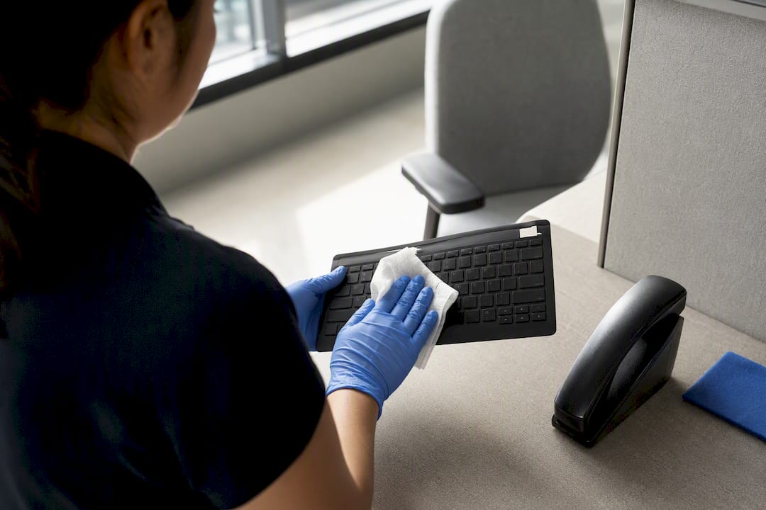 Cleaner wiping an electronics-safe keyboard cover