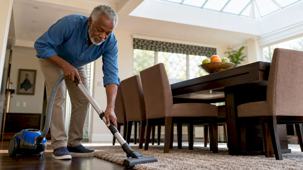 Man vacuuming carpet near window for air quality