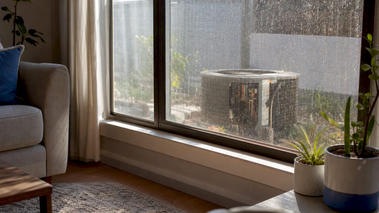 Close-up of dirty window with visible grime and HVAC hints