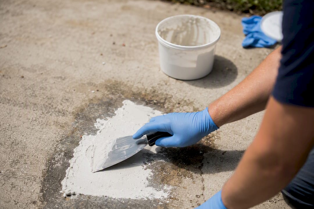 Applying poultice paste on driveway oil stain