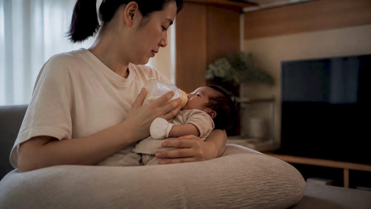 Mother's arms resting on nursing pillow feeding baby