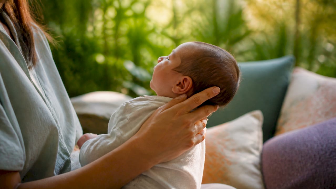 Hand supporting newborn's neck in upright hold