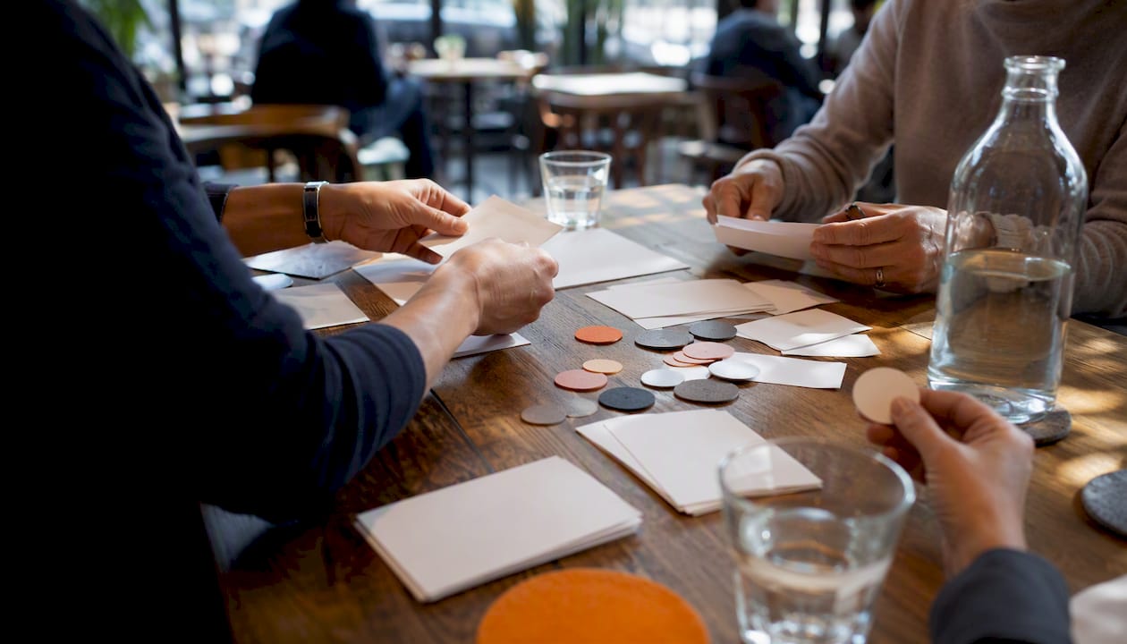 Hands arranging anonymous scorecards and tokens on table