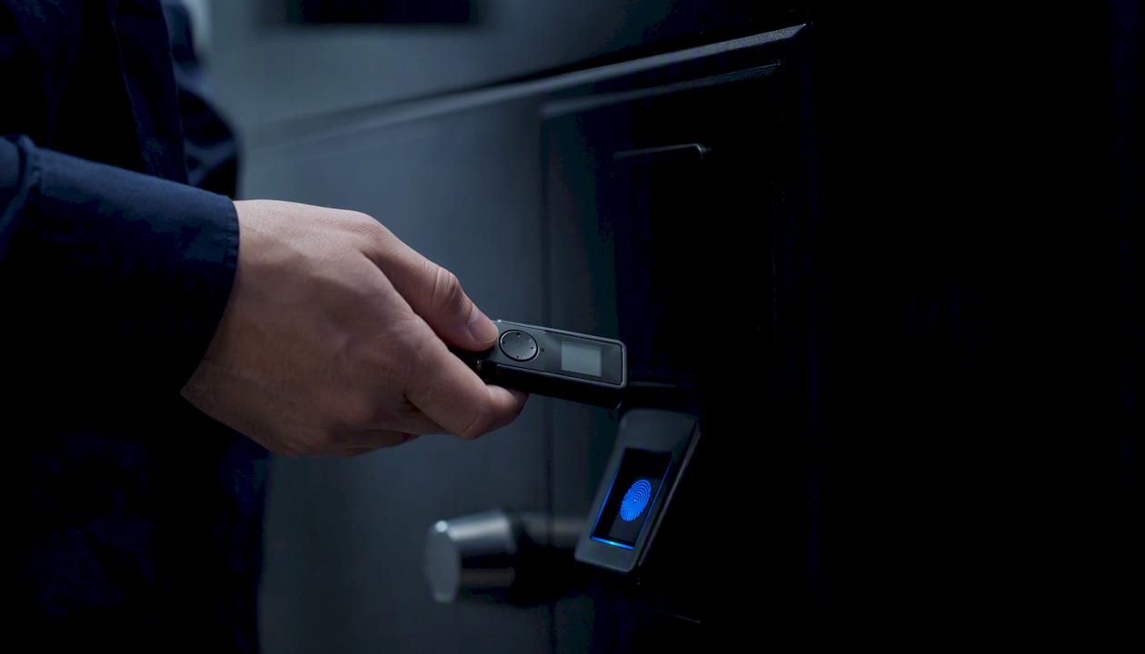 Hand holding security token near locked safe