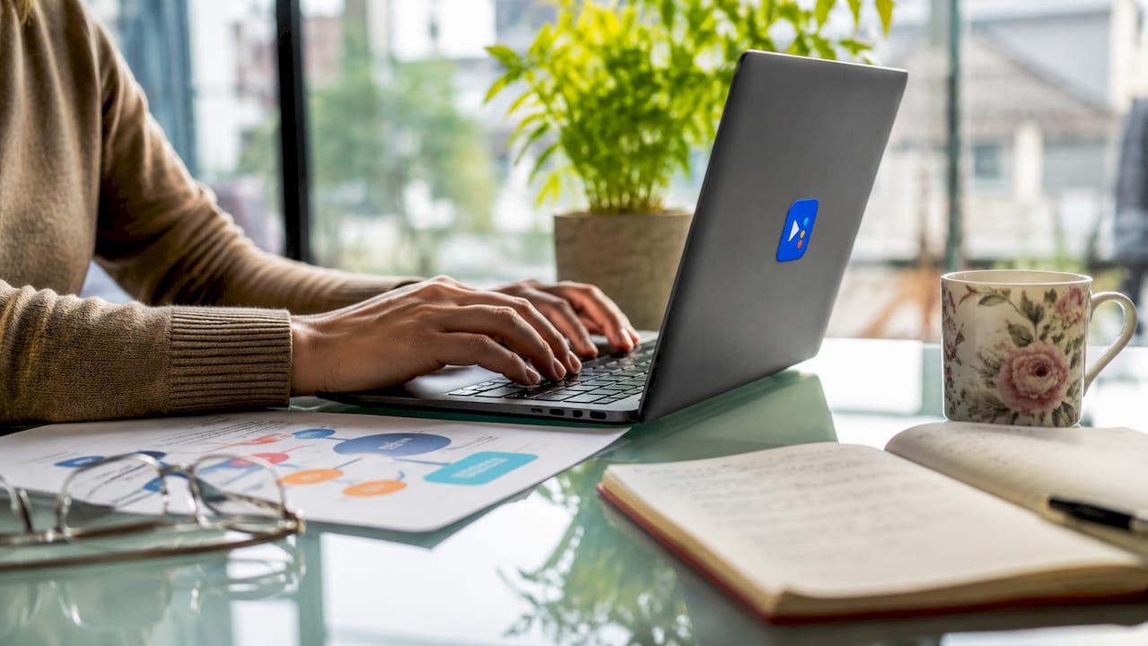Hands typing on laptop with SEO notes and glasses