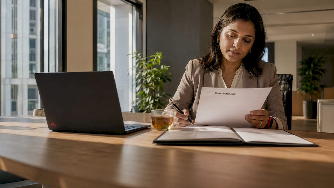 Woman reviewing compliance risk documents in office