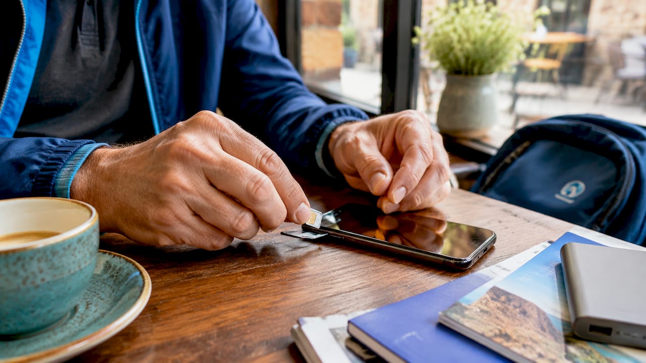 Hands swapping local SIM card into smartphone