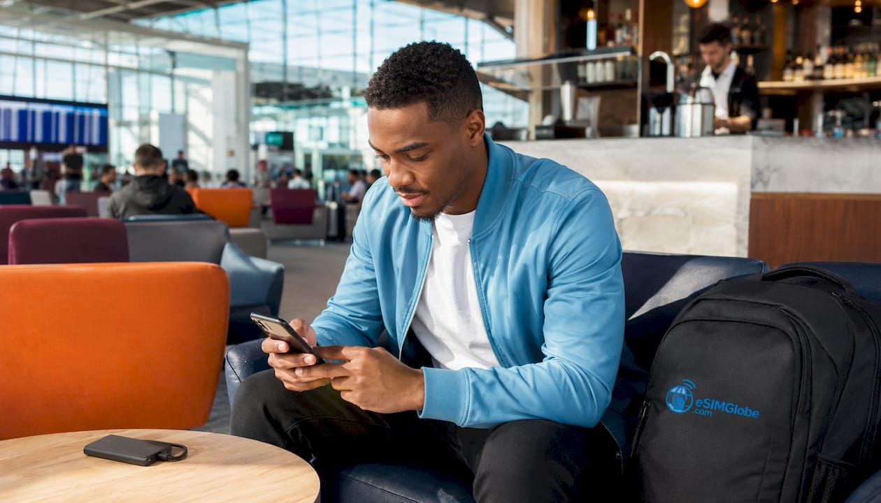 Hands installing eSIM on iPhone in airport lounge