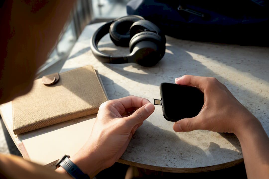Hands inserting SIM tray into smartphone before travel