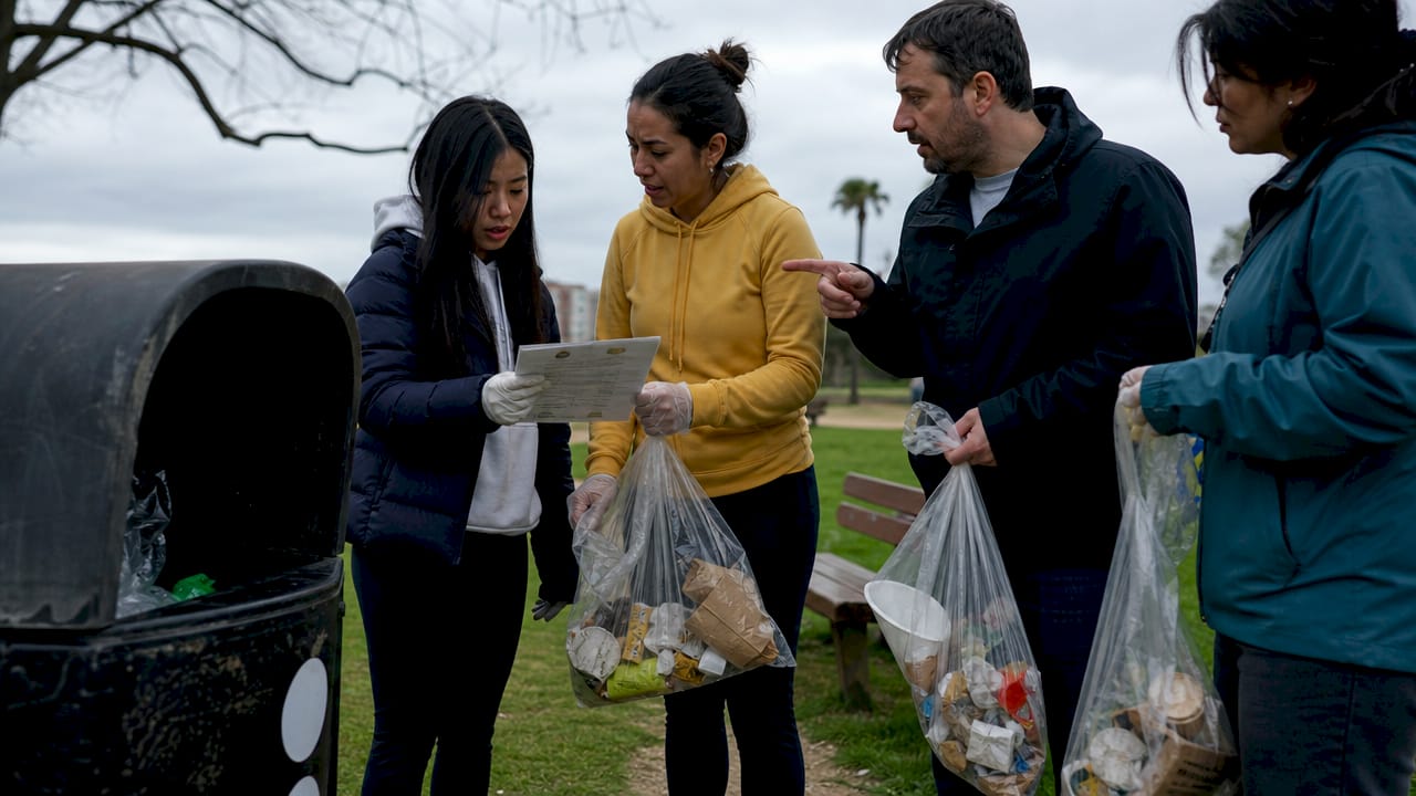Vecinos depositando y clasificando basura en los contenedores de la calle