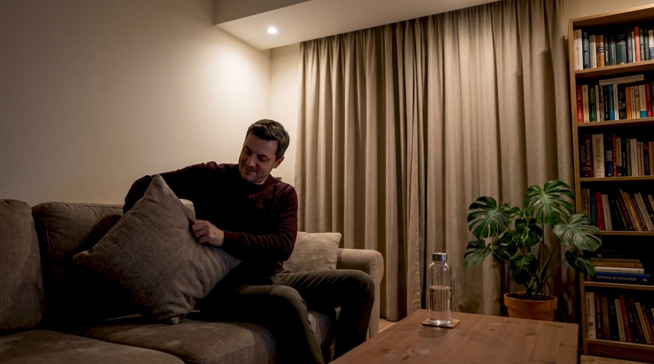 Un bărbat se bucură de liniște, odihnindu-se într-o cameră cu draperiile blackout trase.