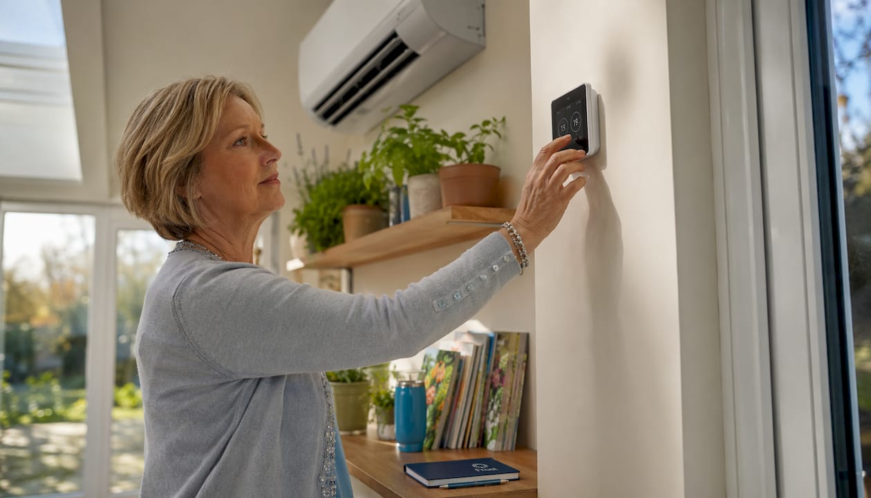 Hand adjusting indoor thermostat near AC unit