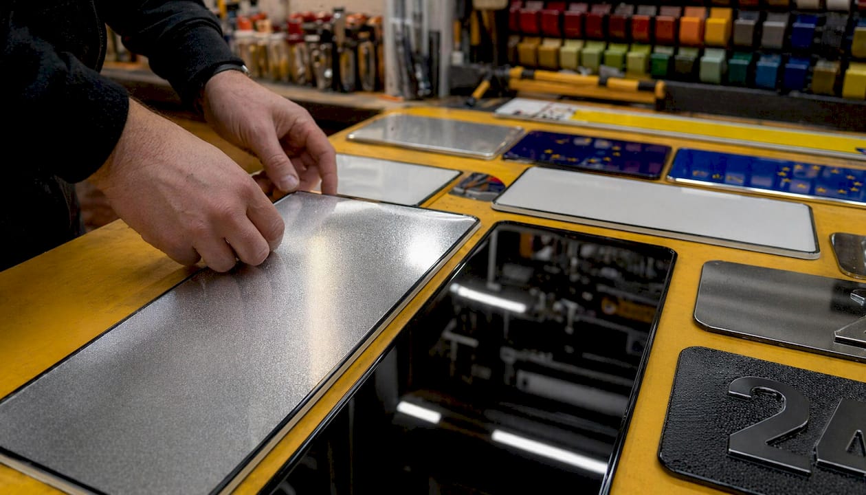 Craftsman hands handling custom vehicle number plates