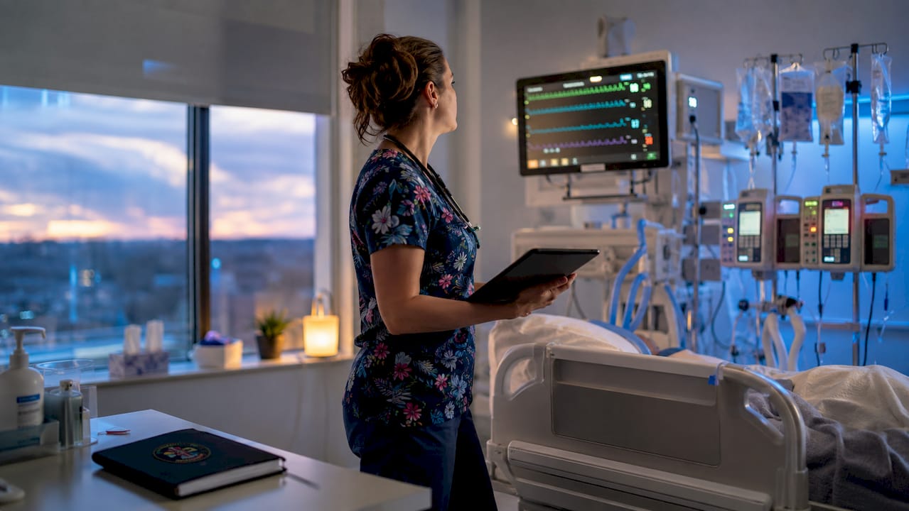 Critical care nurse assessing sepsis patient monitor