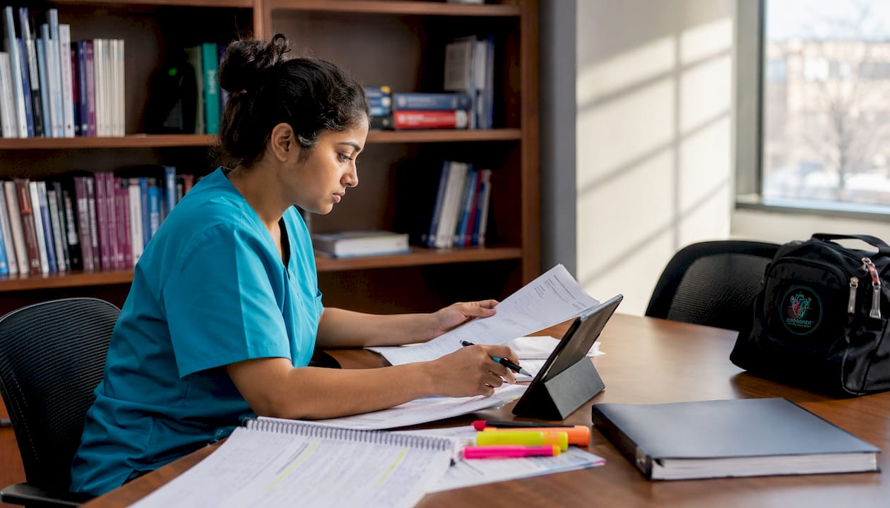 Nurse reviewing CCRN question bank materials at workstation