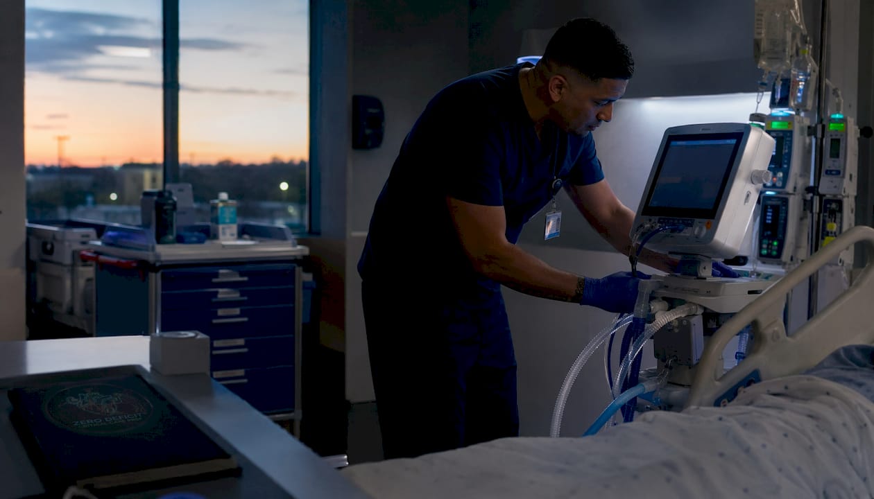 Nurse adjusting ventilator in ICU