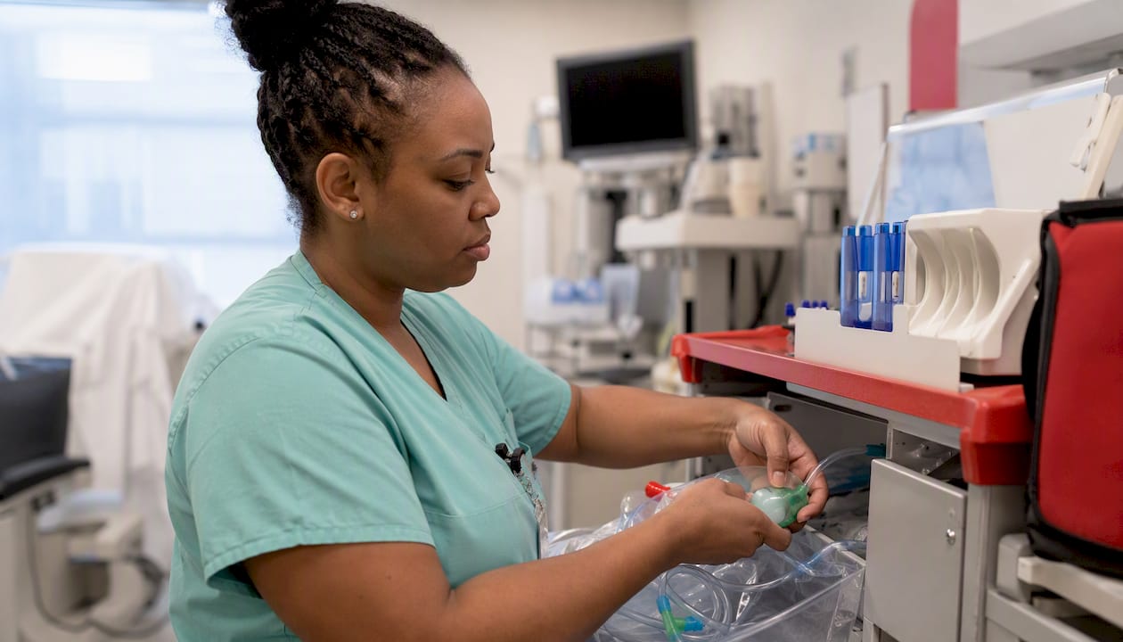 ICU nurse preparing ventilator equipment at bedside