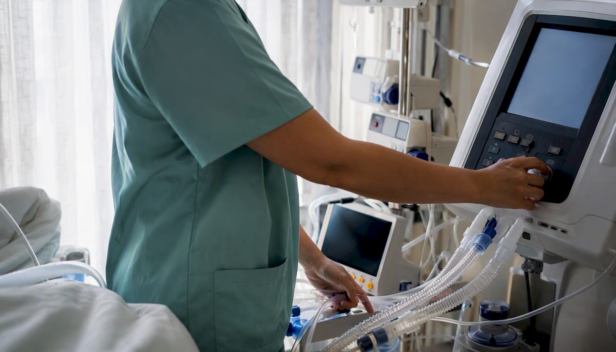 Nurse adjusting ventilator settings at bedside