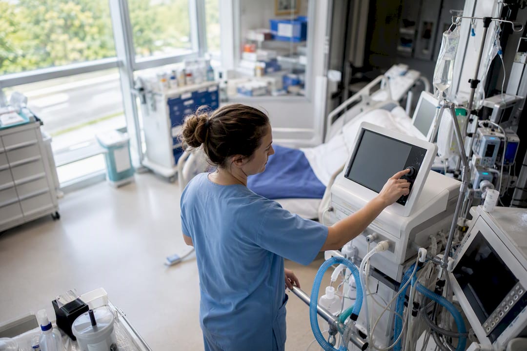 Nurse adjusting ventilator settings in ICU