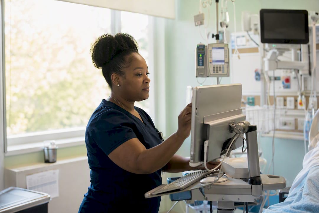Critical care nurse adjusting bedside workstation