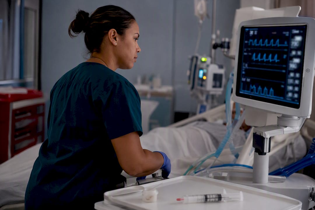 Nurse performing bedside RASS assessment near ventilator