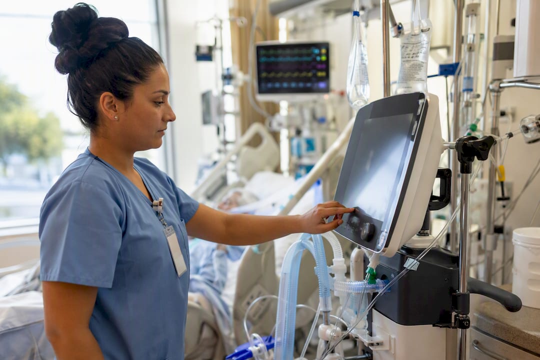 Nurse carefully adjusting ventilator settings in ICU