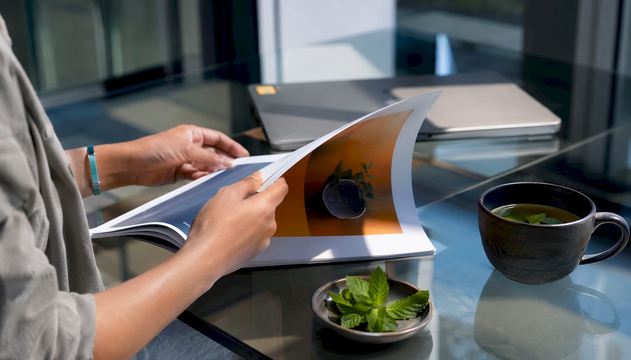 Hands flipping startup accelerator booklet with botanical accents