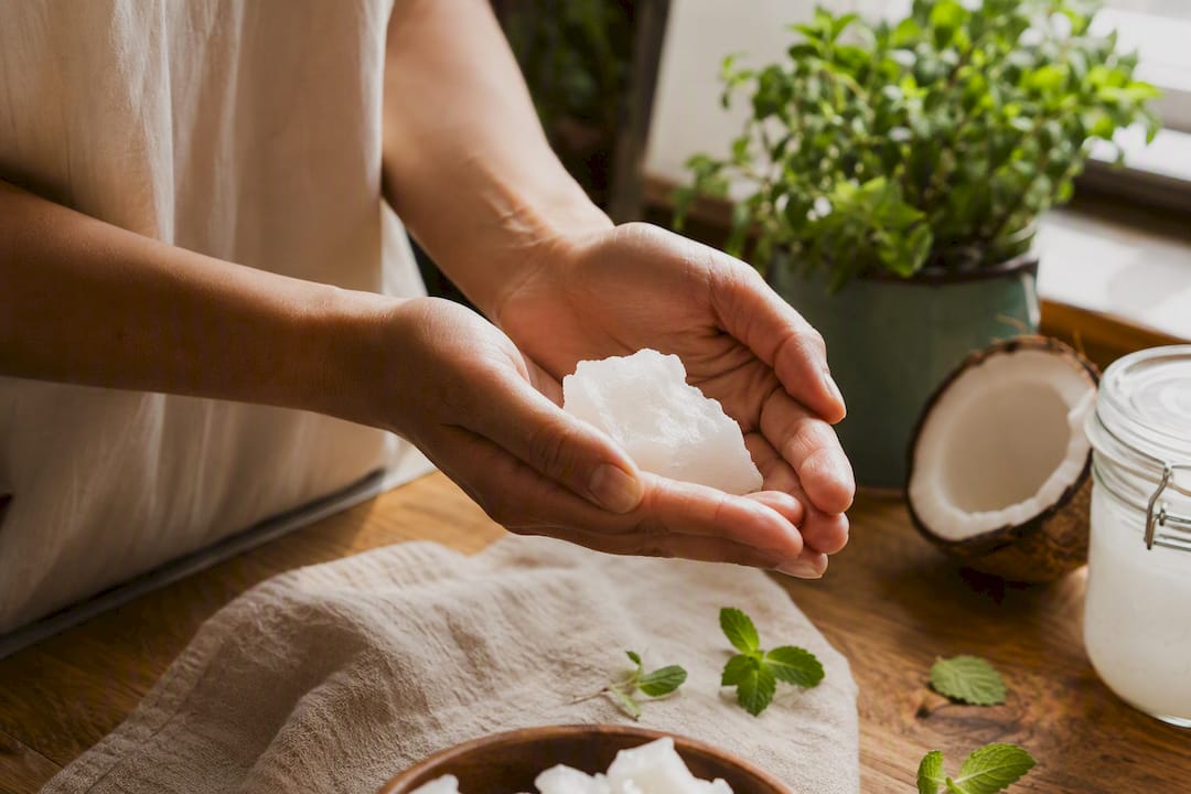 Hands warming solid coconut oil before oil pulling