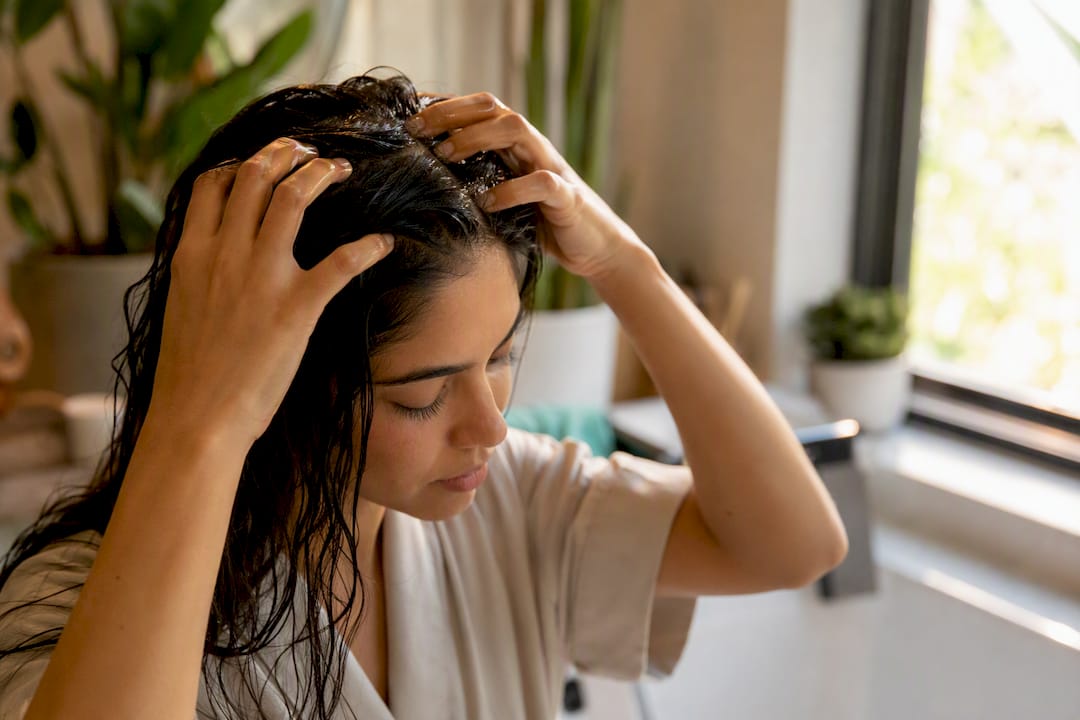 Fingers massaging castor oil into scalp