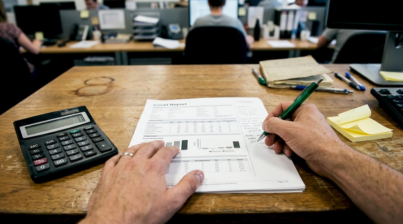 Hands annotating printed credit report details