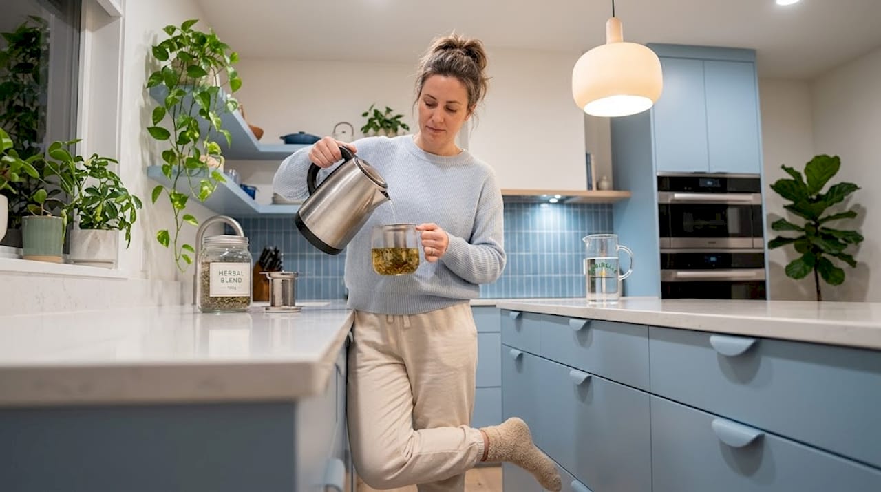 Woman pours herbal sleep tea in cozy kitchen