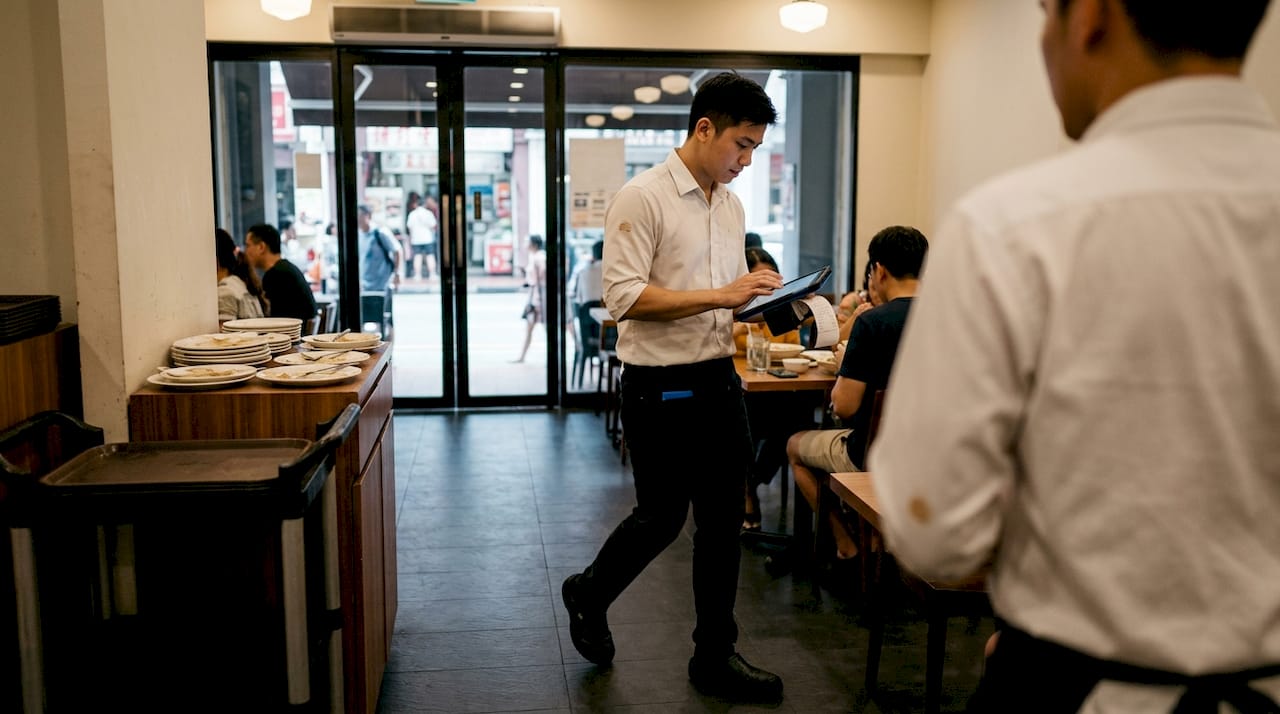 Server carrying POS device near kitchen