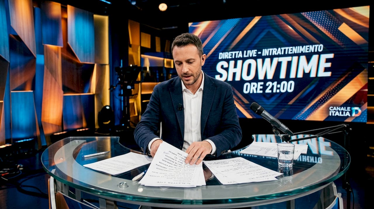 Il conduttore del programma televisivo si prepara dietro le quinte, pronto a entrare in studio per la diretta.