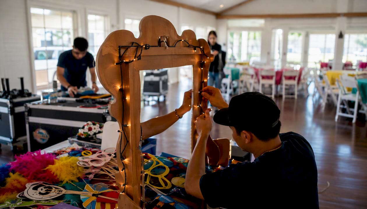 Party staff setting up lighting and photobooth indoors