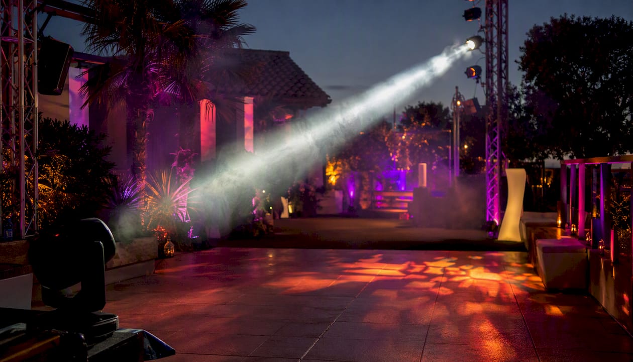 Moving head beam light sweeping a dance floor