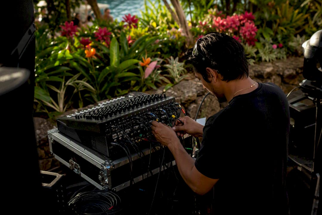 Hands setting up DJ audio mixer cables outdoors