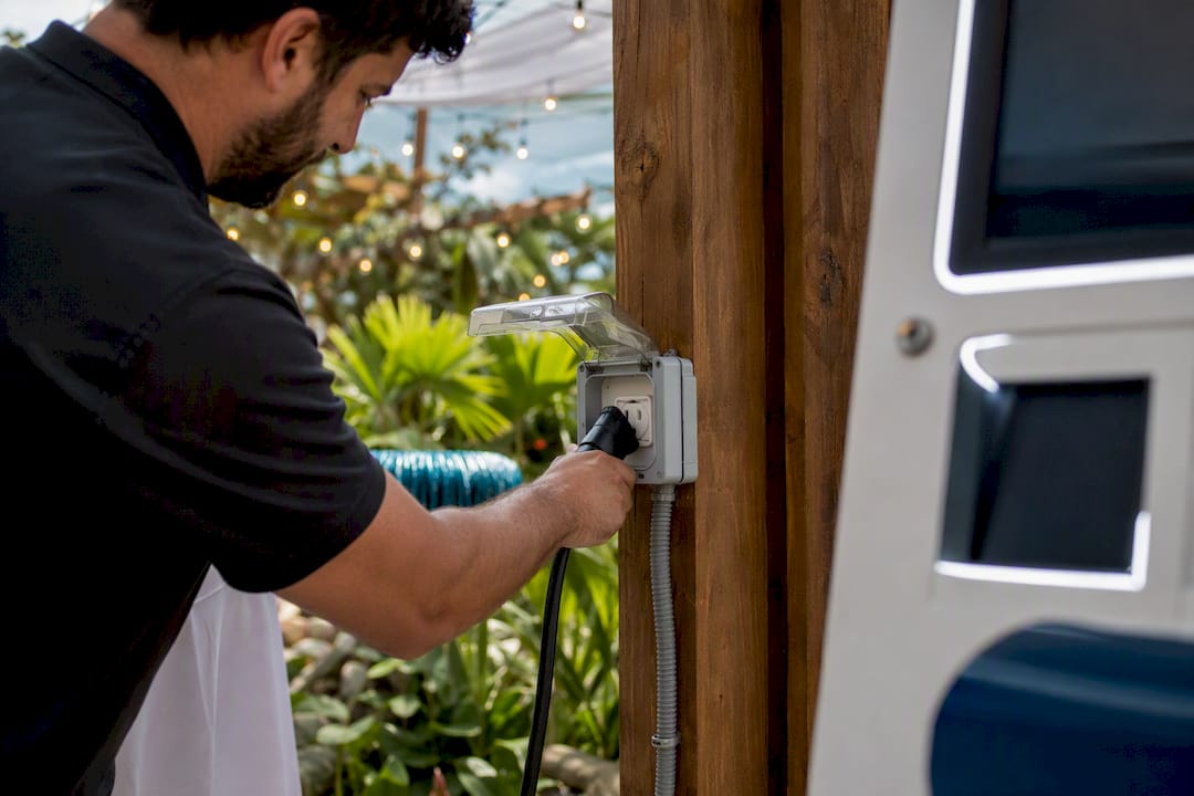 Hands plugging heavy cable into outdoor power outlet