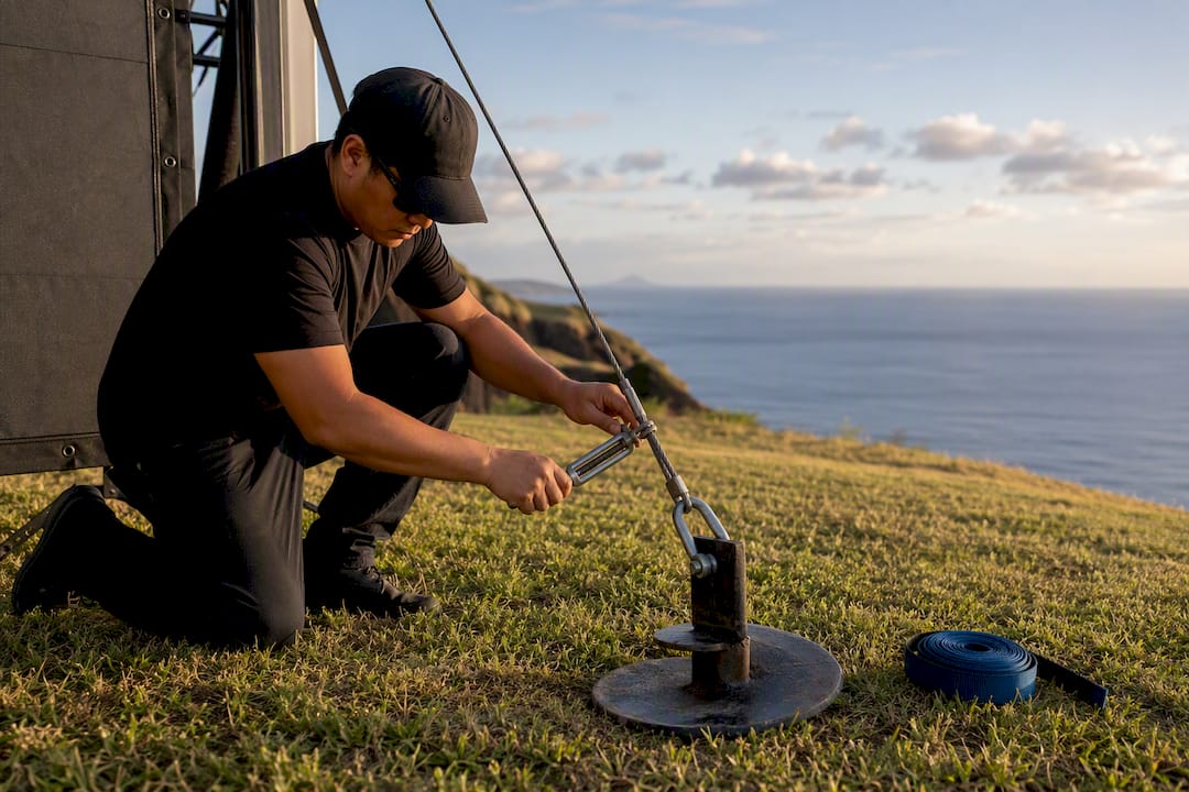 Ground anchor securing outdoor screen in wind