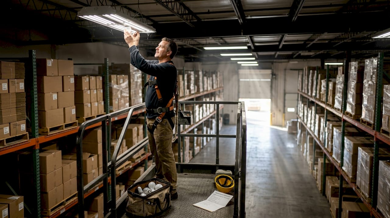 Worker replacing high bay warehouse LED light