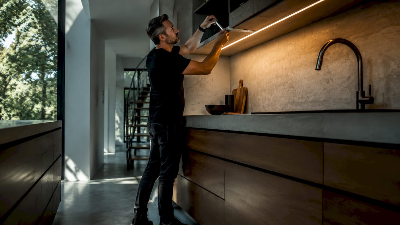 Hands adjusting undercabinet LED kitchen lighting