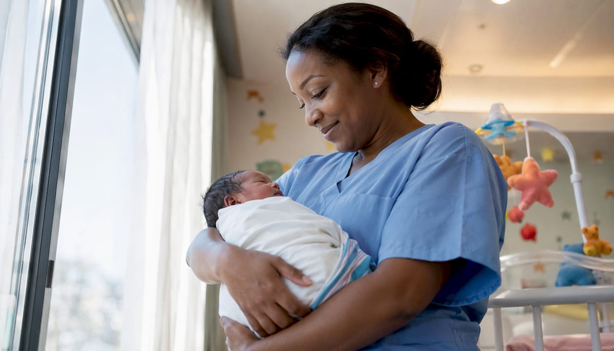 Nurse holding newborn in hospital nursery