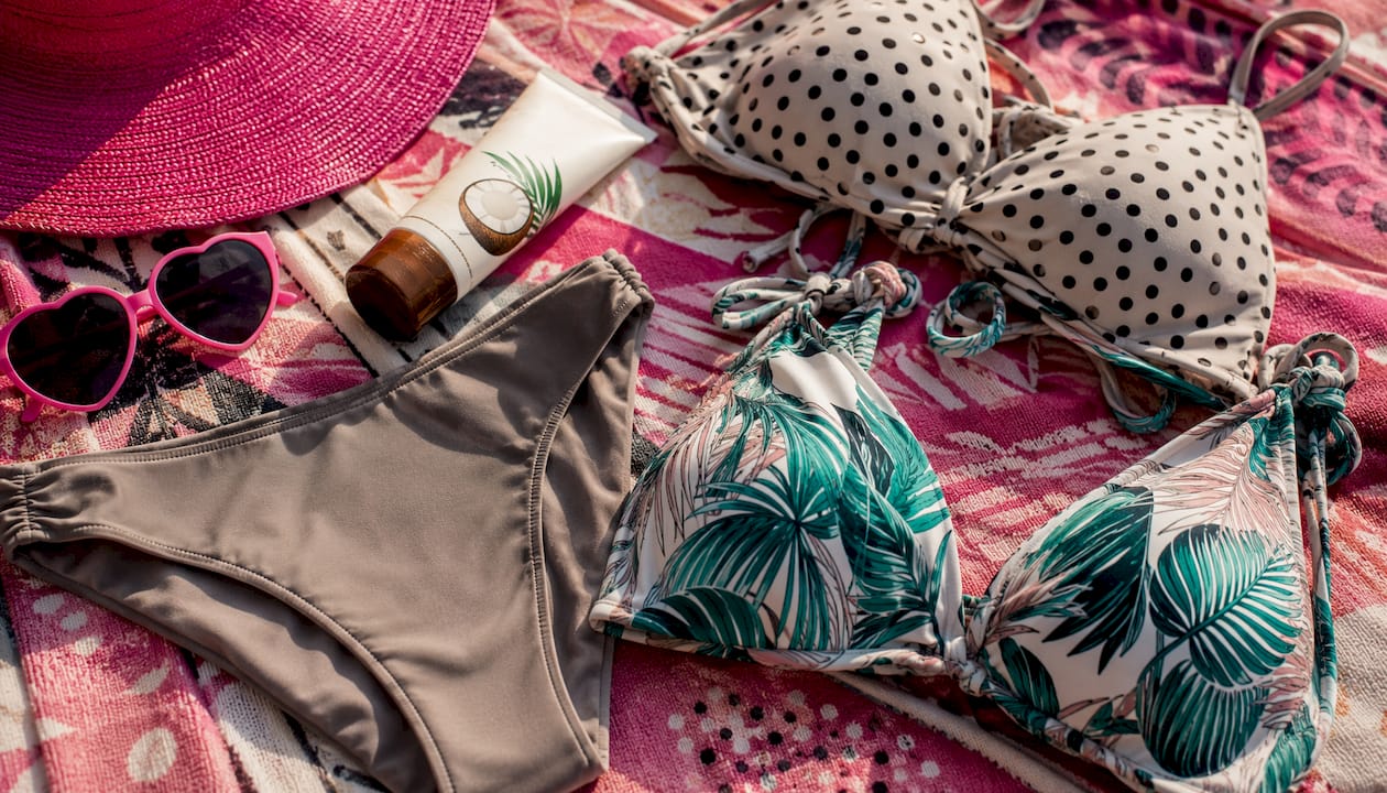 Flat lay of neutral solid bottoms and printed bikini tops