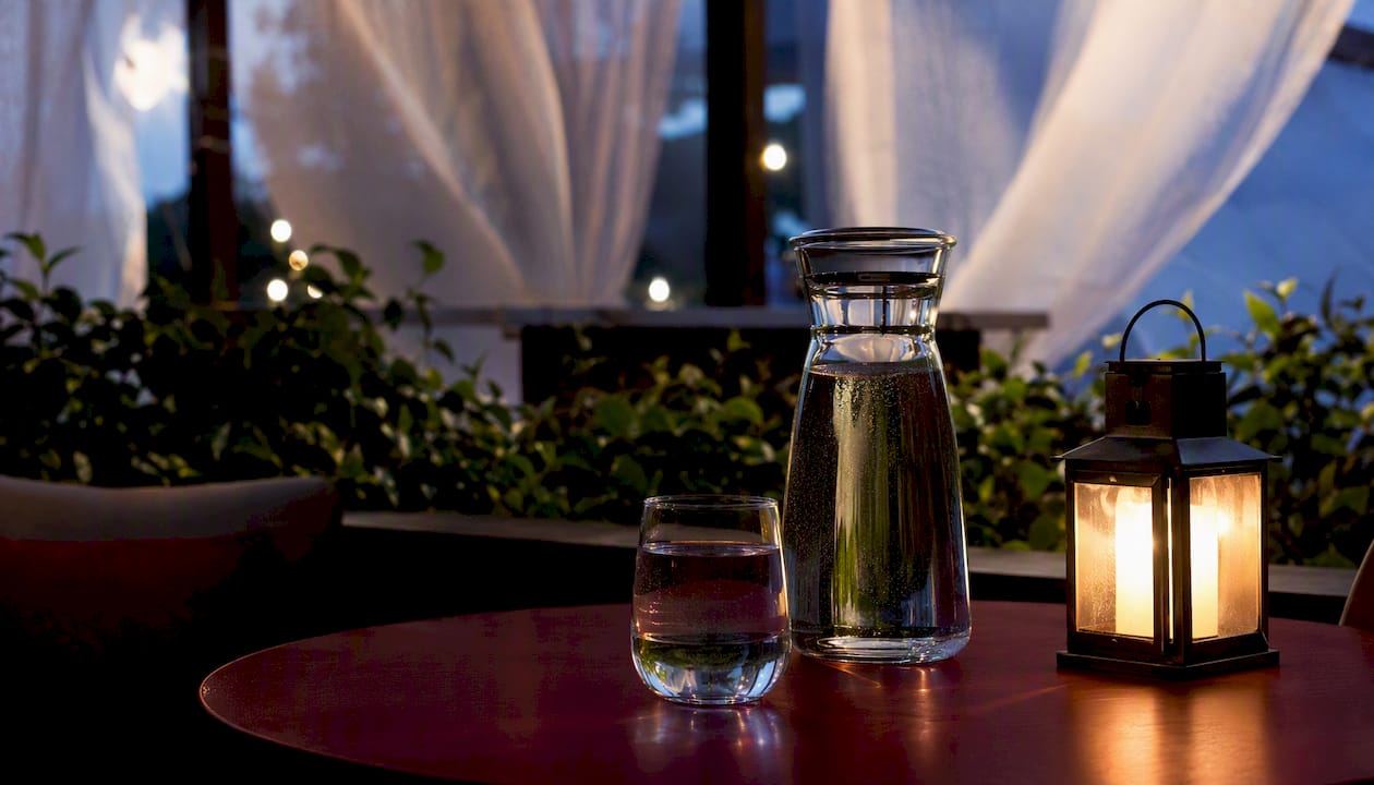 Water carafe and glass on bedside table at night