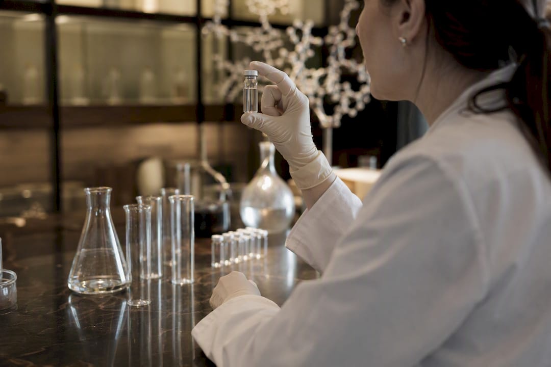 Gloved hands holding vial in clinical research lab