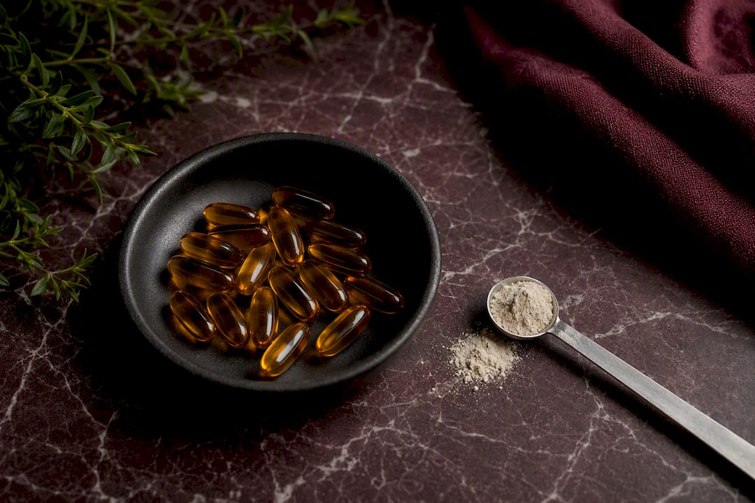 Softgel capsules and powder on slate with measuring spoon
