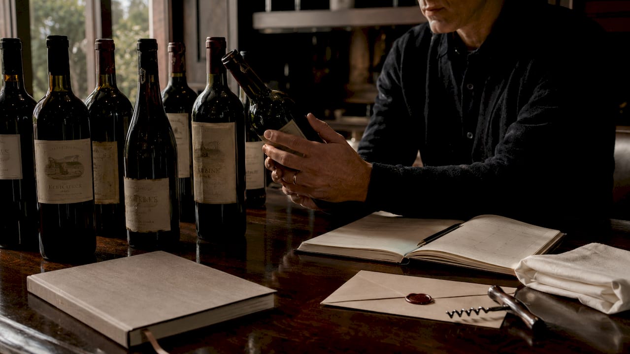 Close-up hands sorting vintage wine bottles in cellar